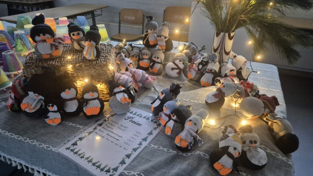 Gebastelte Pinguine zwischen Lichterketten auf einem Verkaufstisch