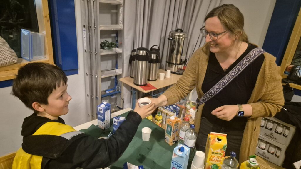 Junge kauft bei einer Mitarbeiterin am Getränkestand