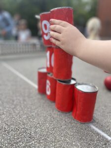 Kinderhand stapelt rote Dosen zu einer Pyramide beim Dosenwerfen
