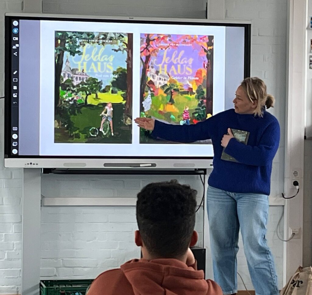 Autorin zeigt den Kindern Illustrationen auf der digitalen Tafel