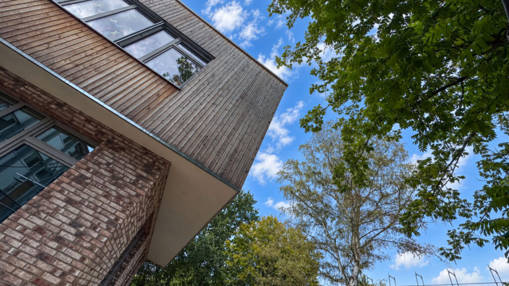Blick an der Fassade aus Klinker und Holz nach oben in die Baumkronen