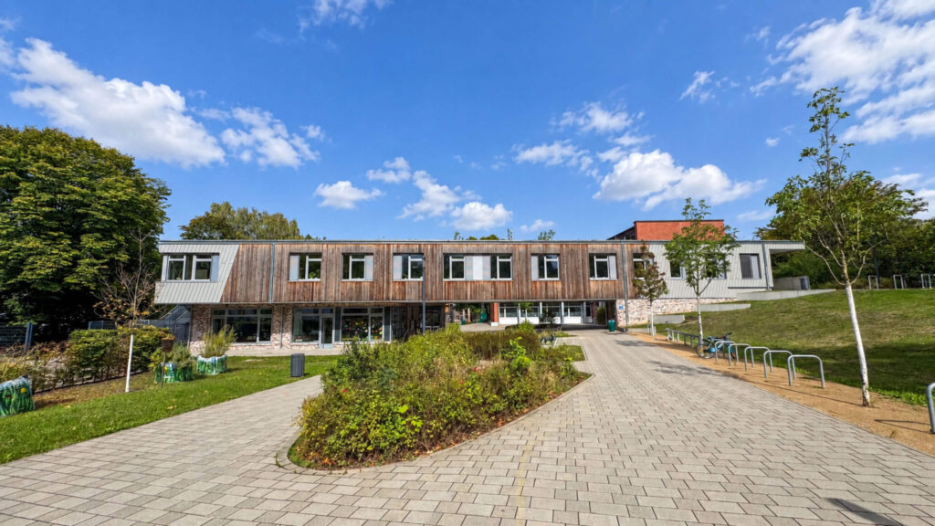 Gepflasterter Weg mit Beet in der Mitte führt zum Schulgebäude