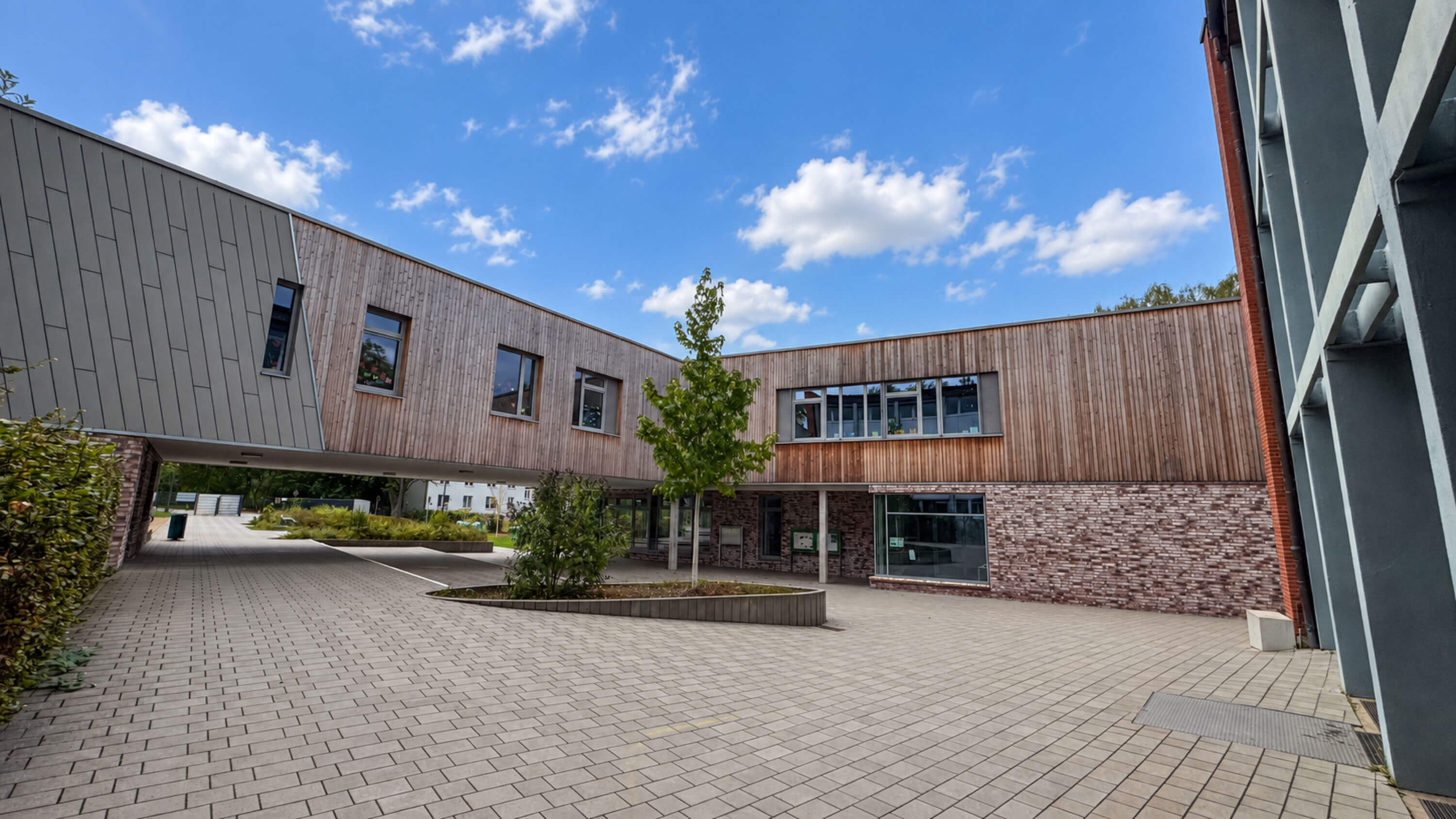 Innenhof zwischen Klinkerbau und holzverkleidetem Neubau