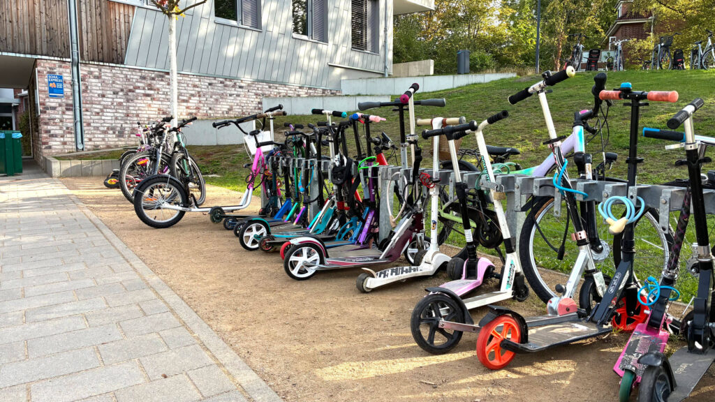 Abgestellte Fahrräder und Roller vor der Schule