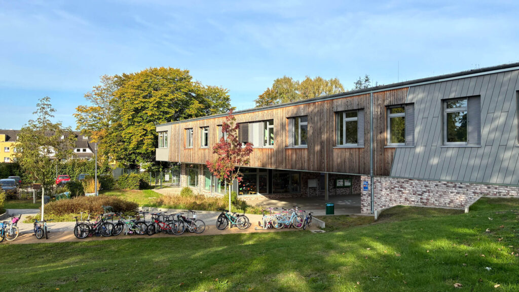 Schulgebäude mit Fahrradständern und Wiese im Sonnenschein
