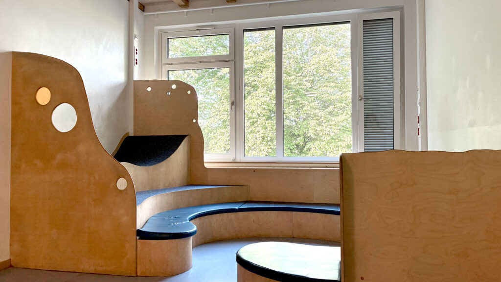Leseecke mit Sitzpodest und runden Holzelementen am Fenster
